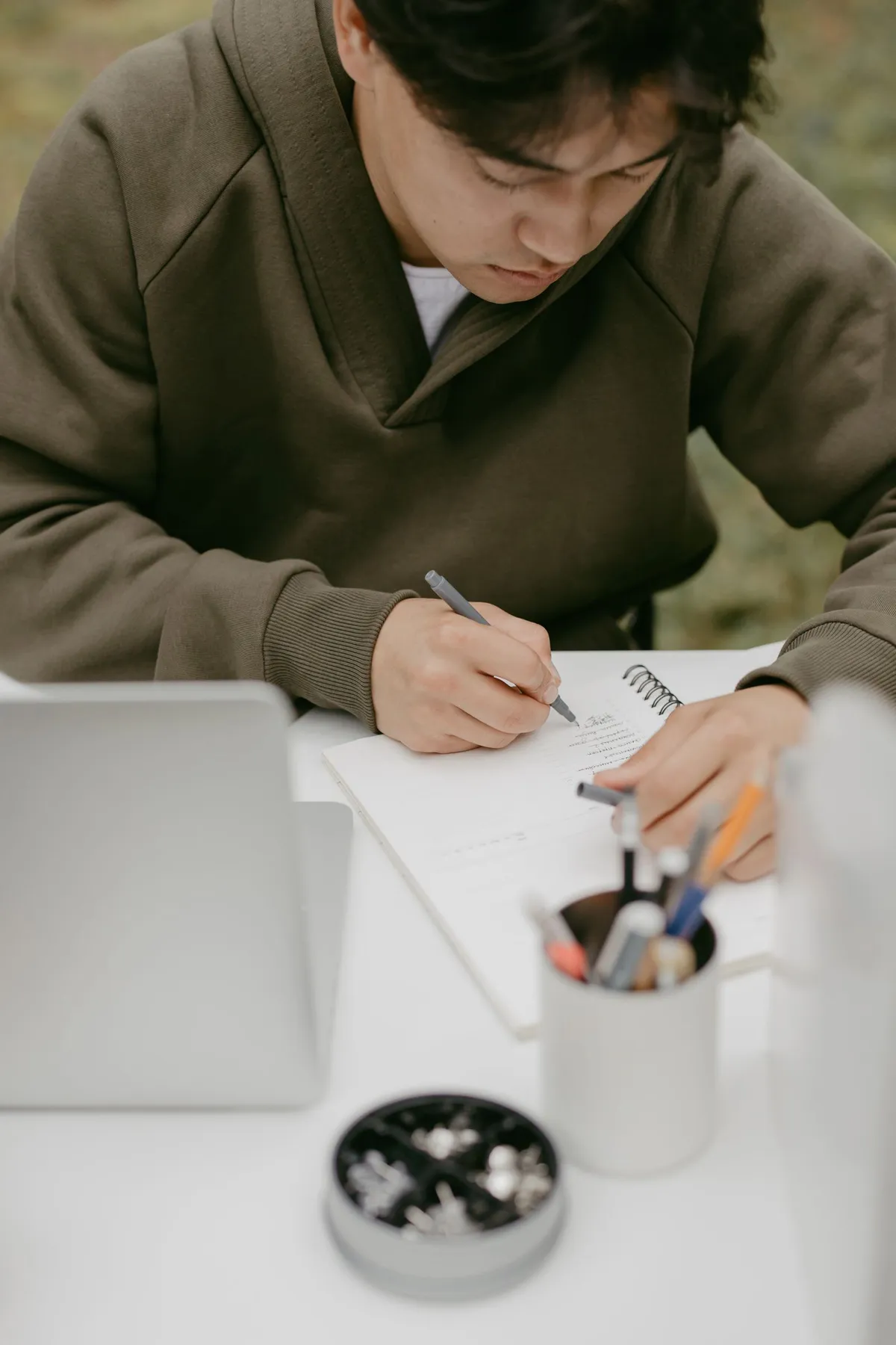 Una persona annota idee su un quaderno, accanto al computer.